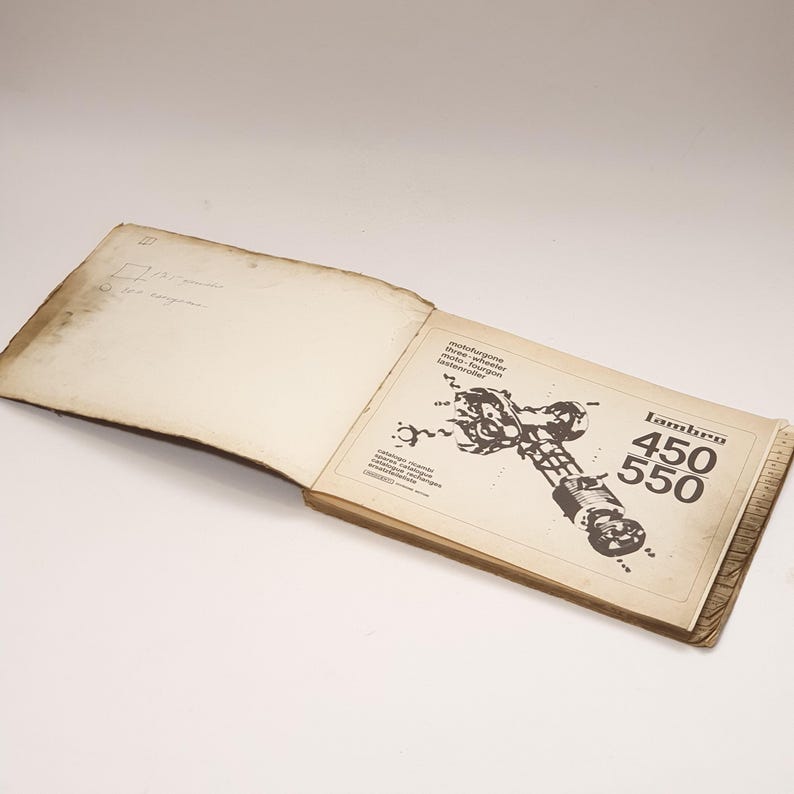 K&ouml;nnte beinhalten: Ein ge&ouml;ffnetes Buch mit einer Schwarzwei&szlig;illustration eines Motorradmotors. Der Buchumschlag tr&auml;gt den Text "Lambro 450 550" in einer fetten, serifenlosen Schrift.
