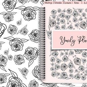 Puede incluir: Una agenda con espiral con un diseño floral. La portada y las páginas interiores presentan un patrón de rosas negras dibujadas a línea sobre un fondo blanco y rosa claro. Las palabras "Yearly Planner" se muestran en la portada.