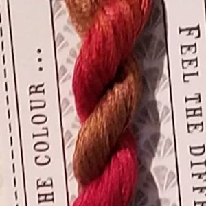May include: A skein of hand-dyed stranded cotton thread in shades of red and gold. The label reads "Mossipot Stranded Cotton" and "Love the Colour". The thread is pre-cut, and the label also says "Feel the Difference".