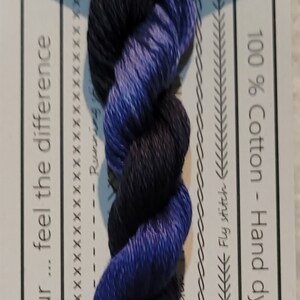 Pode incluir: Fio de bordar de algodão torcido em gradiente de azul escuro a roxo, rotulado como "Bower Bird". A etiqueta indica que o algodão é tingido à mão na Austrália e pré-cortado em comprimentos de 50 cm. Inclui informações sobre tipos de pontos.