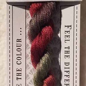 May include: A skein of hand-dyed stranded cotton embroidery floss in shades of green, red, and brown. The label reads "Lillipilli No. 504 10m Pre-Cut Stranded Cotton CGT Hand Dyed Love the Colour... Feel the Difference".