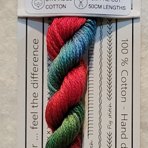 Pode incluir: Meada de fio de algodão torcido "VD 02 King Parrot", nas cores vermelho, verde e azul. A etiqueta indica 10 m de fios pré-cortados de 50 cm e a frase "Love the colour... feel the difference."