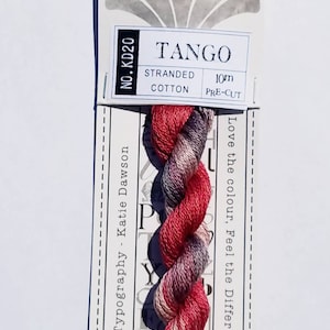May include: A skein of pink, red, and purple embroidery floss labeled "TANGO" with the text "Typography - Katie Dawson" and "NO. KD20" on the packaging. The floss is 10 meters long and is pre-cut.