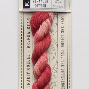 May include: A skein of hand-dyed stranded cotton embroidery floss in shades of pink and red. The floss is labeled "La Cerise" and is 10 meters long. The label also says "Traditionelle Brenda Ryan" and "Hand Dyed".