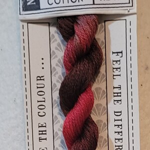 May include: A skein of hand-dyed stranded cotton thread in shades of red and brown, labeled "MAILBOX" and "NO.2005." The label includes the text "LOVE THE COLOUR" and "FEEL THE DIFFERENCE."