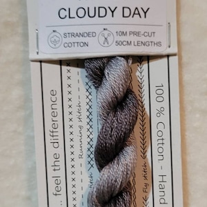 May include: Stranded cotton thread labeled "Cloudy Day" with a gray and white gradient. The label includes the text "100% Cotton - Hand dyed in Australia" and various stitch examples. The thread is 10 meters pre-cut in 50cm lengths.