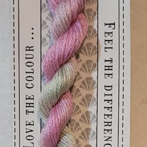 May include: A skein of hand-dyed Sweet Pea stranded cotton embroidery floss in a pink and green color combination. The floss is pre-cut and measures 10 meters. The label reads "LOVE THE COLOUR... FEEL THE DIFFERENCE CGT HAND DYED NO. 100 SWEET PEA STRANDED COTTON 10M PRE-CUT"