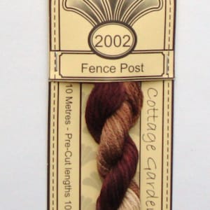 May include: A skein of brown, tan, and burgundy embroidery floss labeled "2002 Fence Post" and "Cottage Garden Threads". The floss is 10 meters long and made of 100% cotton.
