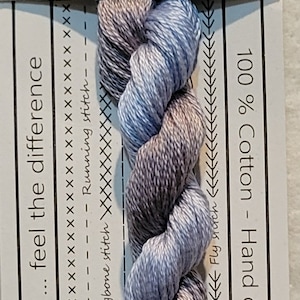 Pode incluir: Um novelo de fio de bordado de algodão trançado azul, cinza e branco, etiquetado como "VD 25 Blue Banded Bee". O fio é 100% algodão e tingido à mão na Austrália. Vem em comprimentos pré-cortados de 10 metros, cada um com 50 centímetros.