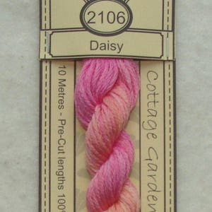 May include: A skein of pink and orange embroidery floss labeled "Cottage Garden Threads" with the number "2106" and the word "Daisy". The floss is 100% cotton and comes in pre-cut lengths.