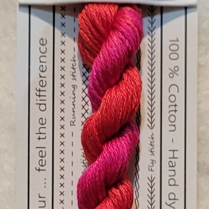 Pode incluir: Um novelo de linha de bordar de algodão Bougainvillea. A etiqueta diz "VD 04 BOUGAINVILLEA" e inclui texto sobre a linha, 100% algodão e tingida à mão na Austrália. A cor transita do vermelho para o rosa.
