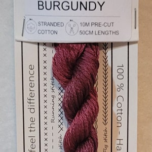 May include: A skein of burgundy stranded cotton embroidery floss, hand-dyed in Australia. The floss is 10 meters long and comes in 50 cm lengths. The label reads "No. 705 BURGUNDY" and "Love the colour... feel the difference".