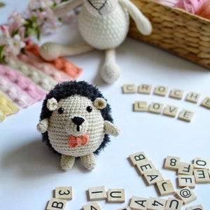 May include: A crocheted hedgehog with a black nose and a pink bow tie, a crocheted sheep, and wooden letter tiles spelling "CROCHE LOVE" and other letters and numbers.