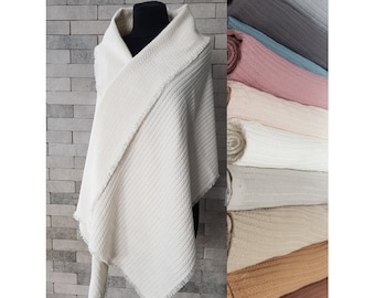 May include: A white, textured, triangular scarf with frayed edges. The scarf is folded in half and draped over a mannequin.