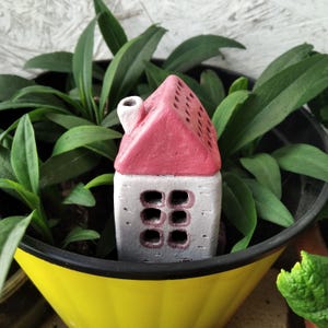 Ett miniatyrhus i lermaterial för att dekorera blomkrukor eller ett florarium.