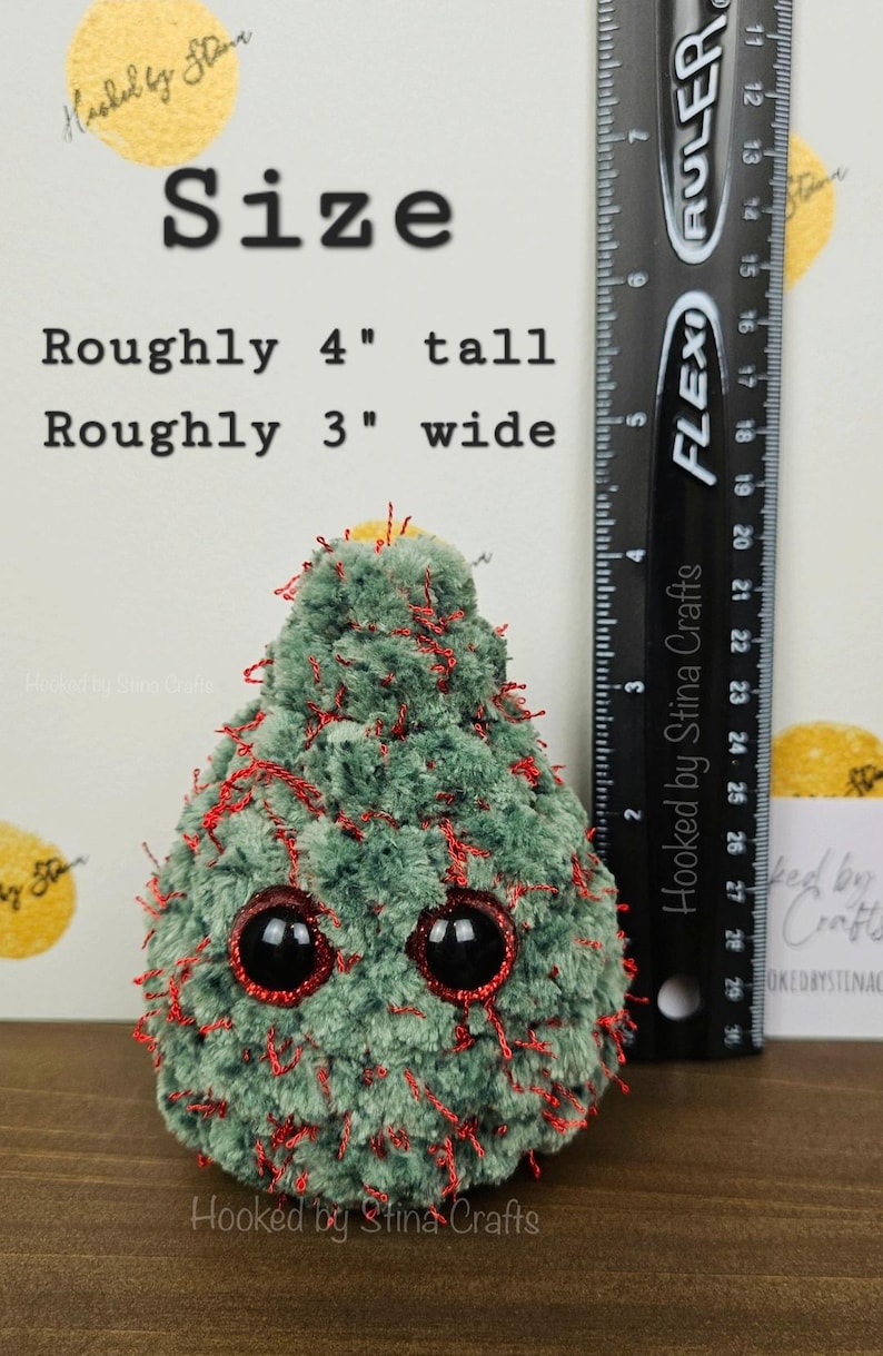 May include: A green and red crocheted Christmas tree plush toy with googly eyes. The toy is approximately 4 inches tall and 3 inches wide. The toy is sitting on a wooden surface.