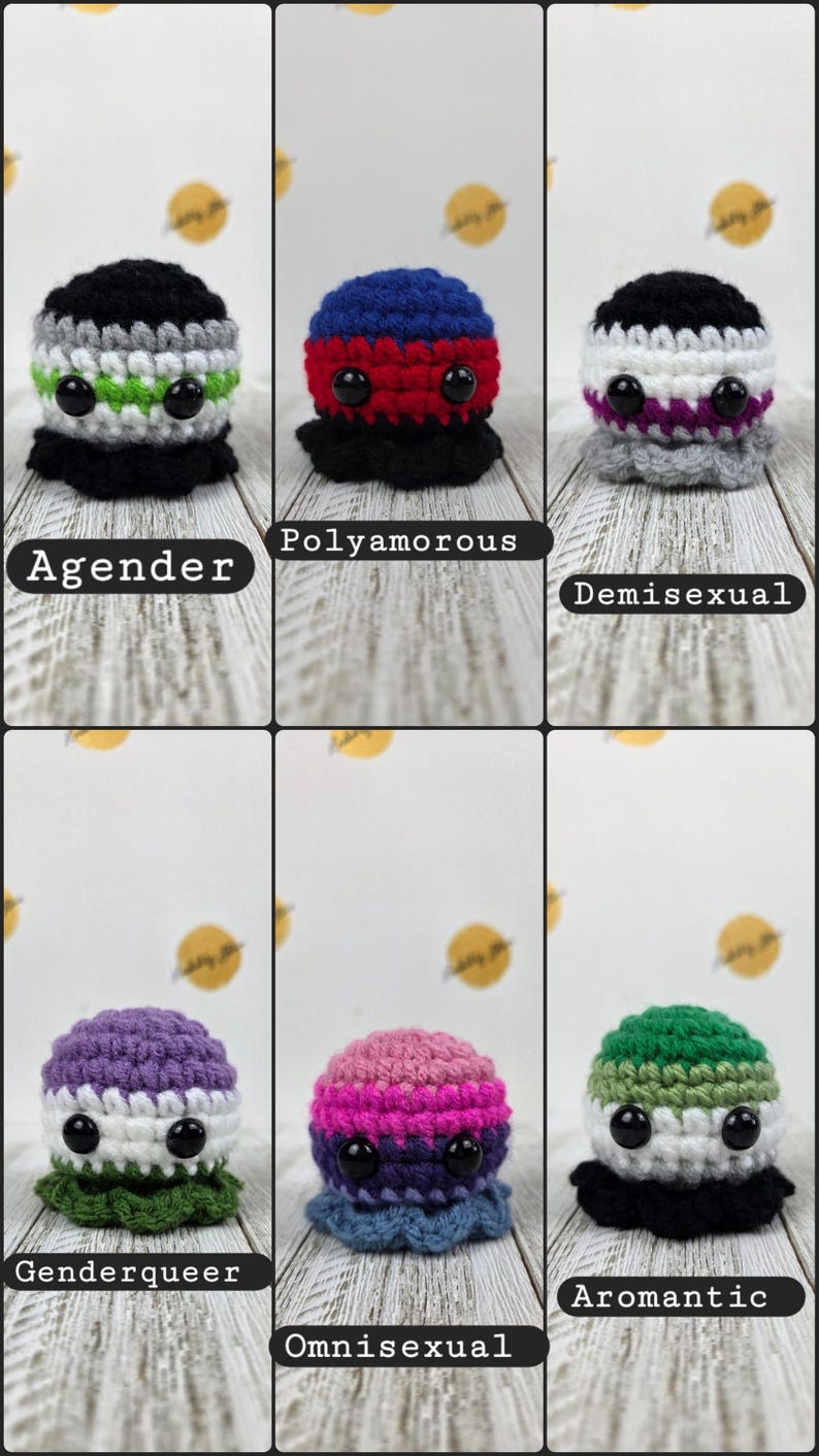 May include: A collection of six crocheted plushies, each with a unique color scheme and design. The plushies are labeled with terms like "Agender," "Polyamorous," and "Demisexual." Each has black button eyes and a ruffled base, with the text labels below.