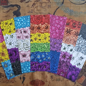 Puede incluir: Conjunto de ocho marcapáginas con diferentes patrones florales en colores arcoíris. Cada marcapáginas es de un color diferente del arcoíris, con un patrón floral que coincide con el color. Los marcapáginas están dispuestos en forma de abanico.