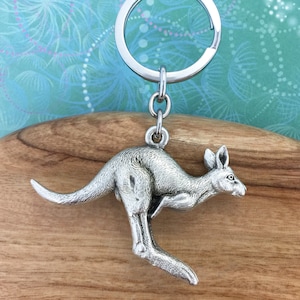 May include: A silver kangaroo keychain with a silver key ring. The kangaroo is in a leaping pose.