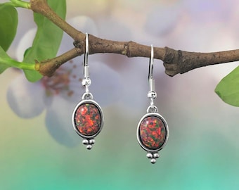 May include: A pair of silver dangle earrings with oval-shaped red and green opal stones.