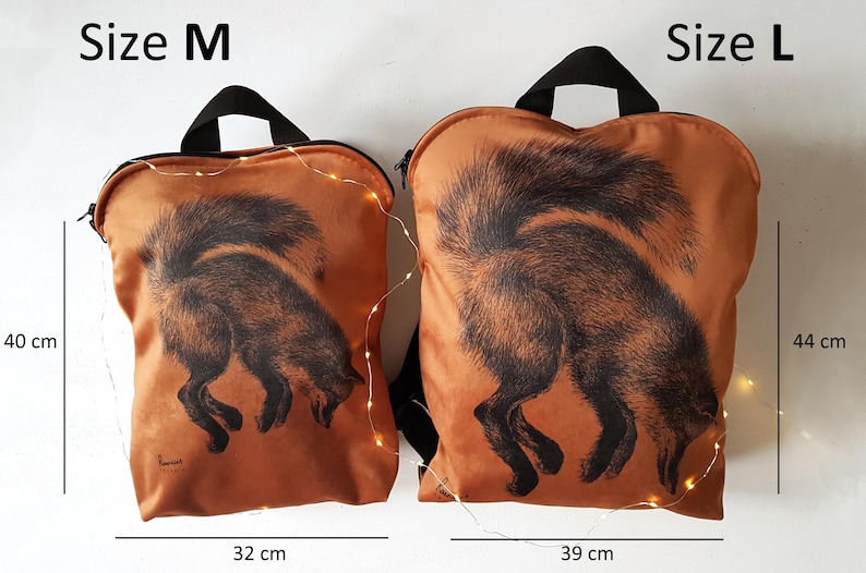 May include: Two orange backpacks with black handles and a black fox illustration. The size M backpack is 40 cm tall and 32 cm wide. The size L backpack is 44 cm tall and 39 cm wide.