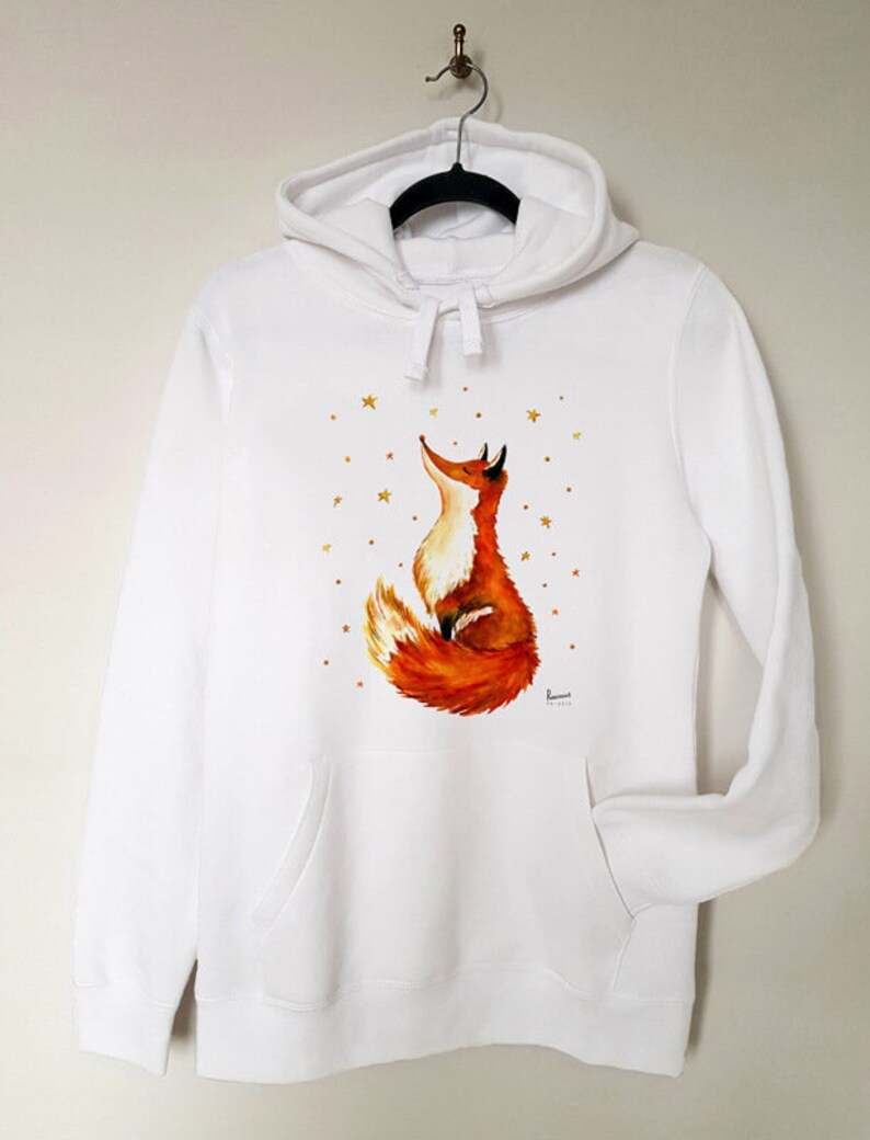 Puede incluir: Sudadera con capucha blanca con un zorro rojo mirando hacia arriba a las estrellas doradas impresas en la parte delantera.