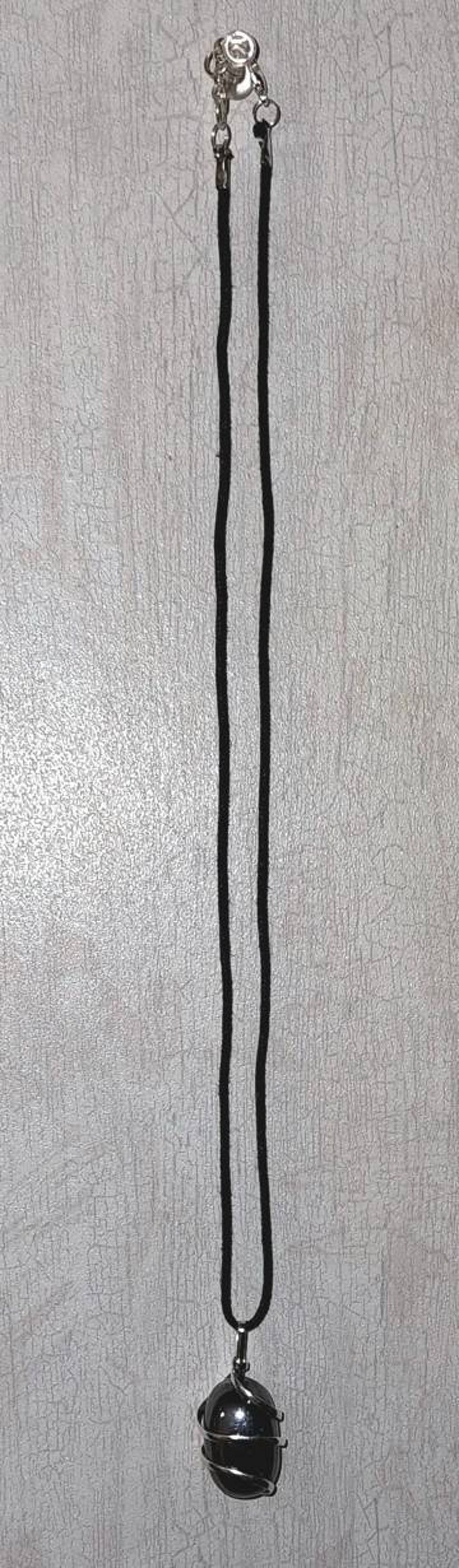 May include: A black gemstone pendant necklace with a silver wire cage. The necklace has a black cord and a silver clasp.