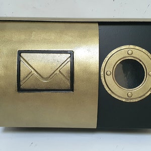 Buzón de pared elegante y moderno, tubo para la prensa, ojo de buey con ventana de visualización, dorado y negro, arte en metal, herrería