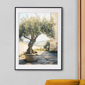 Könnte beinhalten: Ein gerahmtes Gemälde eines großen Olivenbaums in einem Terrakotta-Topf mit Blick auf sanfte Hügel im Hintergrund. Der Baum steht in einem Innenhof mit Steinplatten.