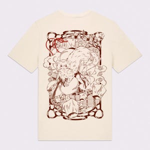 May include: A cream-coloured t-shirt with a brown illustration. The design features a ferret, lanterns, and floral elements, creating a whimsical and artistic aesthetic. The artwork is detailed and stylized.