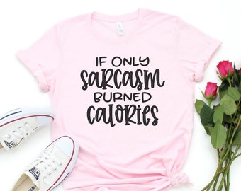 Puede incluir: Una camiseta rosa claro con el texto "IF ONLY SARCASM BURNED CALORIES" en negro. Zapatillas blancas y un ramo de rosas rosas también están en la imagen.