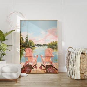 May include: A framed painting depicts two coral-colored Adirondack chairs on a wooden dock overlooking a serene lake scene. The sky is a blend of blue and pink hues, with trees lining the distant shore. The artwork evokes a sense of tranquility.