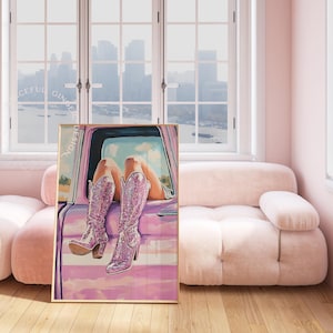 May include: A framed art print featuring a woman's legs in sparkly pink boots, resting on a pink car door. The artwork has a soft, painterly style with a pink and purple color palette. The word "DESIGN" is printed vertically on the left side of the frame.
