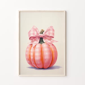 Puede incluir: Una impresi&oacute;n enmarcada que presenta una calabaza rosa con un lazo de cuadros. La calabaza es de un tono rosa vibrante con un patr&oacute;n a cuadros. El lazo es de cuadros rosas a juego. La obra de arte est&aacute; sobre un fondo blanco roto.