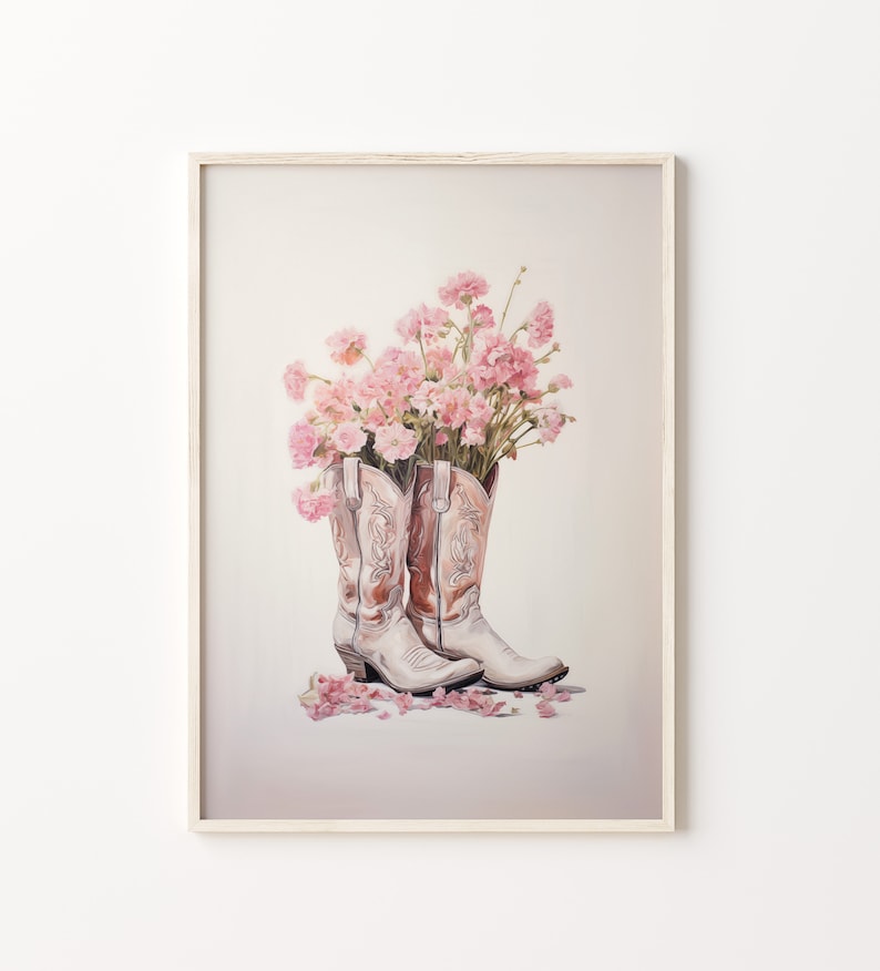 May include: A pair of white cowboy boots with pink flowers in the tops. The boots are on a white background with pink flower petals scattered around them.