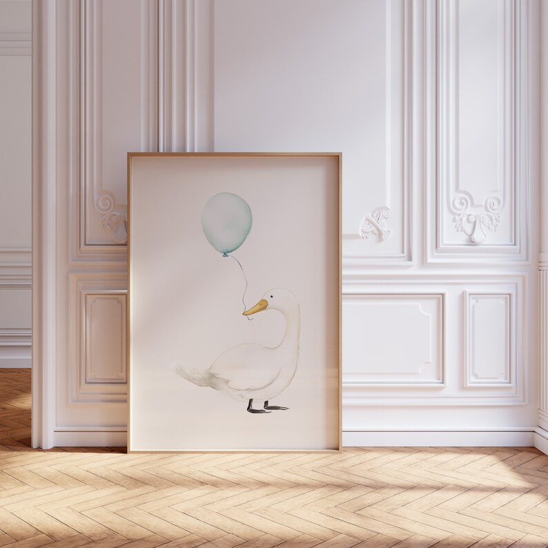 May include: A framed watercolor print featuring a white goose holding a light blue balloon. The goose has a yellow beak and black feet. The artwork is displayed in a room with white paneling and a wooden floor, creating a soft, whimsical aesthetic.