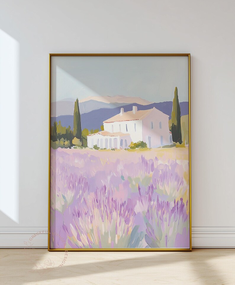 Large framed painting of a lavender field landscape with a cream-colored villa in the distance. The bold golden frame contrasts with the delicate hues of lilac, sage, and rose in the artwork.