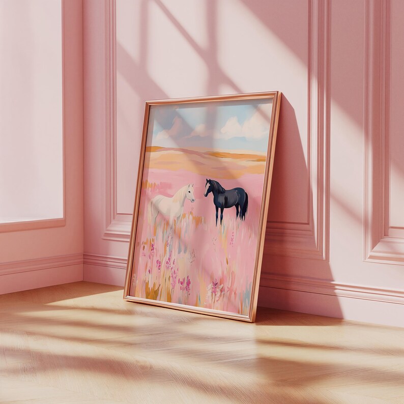 May include: A framed painting of two horses in a field. The horse on the left is white and the horse on the right is black. The field is a soft pink color with a blue sky in the background.