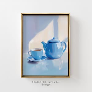 Puede incluir: Impresión artística enmarcada que presenta una tetera azul, una taza y un platillo. La taza contiene té. La obra de arte tiene un estilo suave y pictórico, con un marco dorado. El texto "GRACEFUL GINGER design" está en la parte inferior.