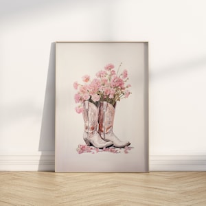 May include: A pair of white cowboy boots with pink floral accents. The boots are filled with pink flowers and petals are scattered on the floor.