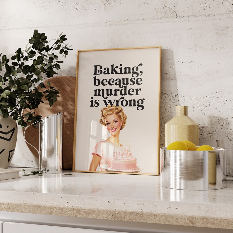 Peut inclure: Une affiche encadr&eacute;e avec une illustration r&eacute;tro d'une femme tenant un g&acirc;teau rose. Le texte sur l'affiche dit "Baking, because murder is wrong."