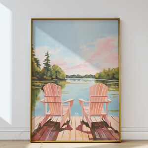May include: A framed art print depicts two pink Adirondack chairs on a wooden dock overlooking a serene lake scene. The sky is a soft blue with pink clouds, and the artwork is framed in gold.