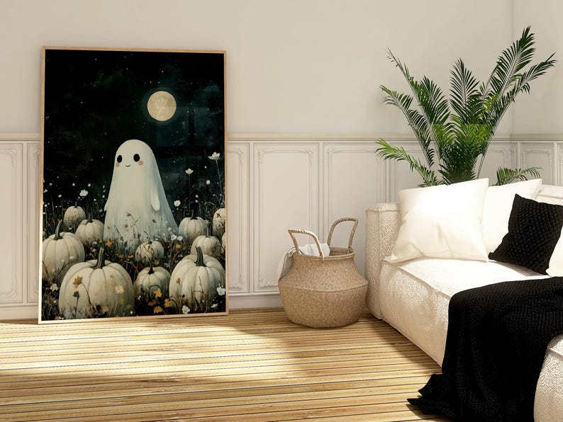 May include: A framed art print featuring a friendly ghost standing among pumpkins under a full moon. The artwork has a whimsical, cartoonish style with a dark, starry background. The pumpkins are white and the ghost is also white.