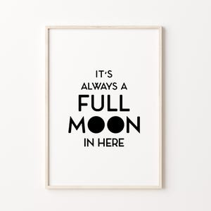 May include: A framed print with the text "IT'S ALWAYS A FULL MOON IN HERE" in black, bold font. The artwork features a minimalist design with a white background and a light-colored wooden frame. The phrase is centered.