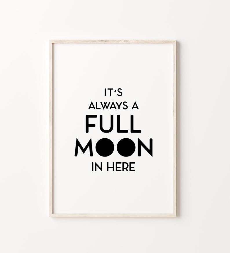 May include: A framed print with the text "IT'S ALWAYS A FULL MOON IN HERE" in black, bold font. The artwork features a minimalist design with a white background and a light-colored wooden frame. The phrase is centered.