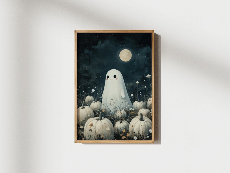 A framed artwork depicts a smiling ghost in a white sheet standing among white pumpkins under a starry night sky with a full moon. The ghost is centered and surrounded by some small flowers. The background is dark with a bluish hue.