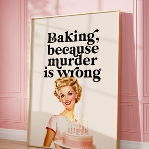 Retro-themed art print with a cheerful woman holding a pink frosted cake. The humorous text reads, "Baking, because murder is wrong." The poster leans against a pink paneled wall.