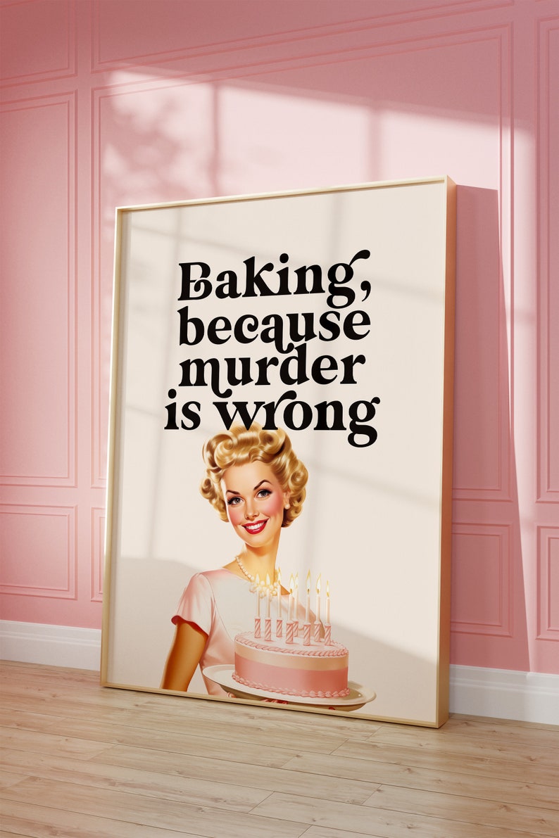 Retro-themed art print with a cheerful woman holding a pink frosted cake. The humorous text reads, "Baking, because murder is wrong." The poster leans against a pink paneled wall.