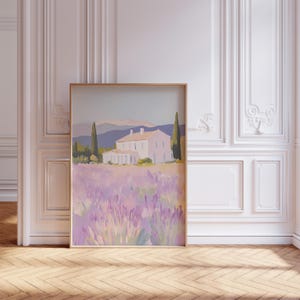 Large lavender field painting leaning against an ornate white paneled wall. The romantic scene showcases a light pink villa nestled among tall trees, with purple flowers stretching across the foreground.