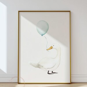 May include: Watercolor illustration of a white duck holding a light blue balloon. The artwork is framed in a gold frame and set against a white background. The duck has a yellow beak and black feet. The balloon is tied to the duck's beak.